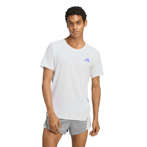En mand med kort, krøllet hår har en Adidas Adizero løbetrøje (herre) i farven White/Solpur på og grå shorts. Løbetrøjen har et lille logo på brystet, mens han står med ansigtet fremad, den ene arm afslappet og den anden let bøjet.