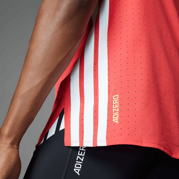 Nærbillede af en person i en Adidas Adizero Running Tee til mænd i Semi Lucid Red, lavet af genanvendt polyester med hvide striber og guld ADIZERO-print nær kanten, sammen med sorte Adizero shorts.