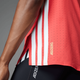 Nærbillede af en person i en Adidas Adizero Running Tee til mænd i Semi Lucid Red, lavet af genanvendt polyester med hvide striber og guld ADIZERO-print nær kanten, sammen med sorte Adizero shorts.