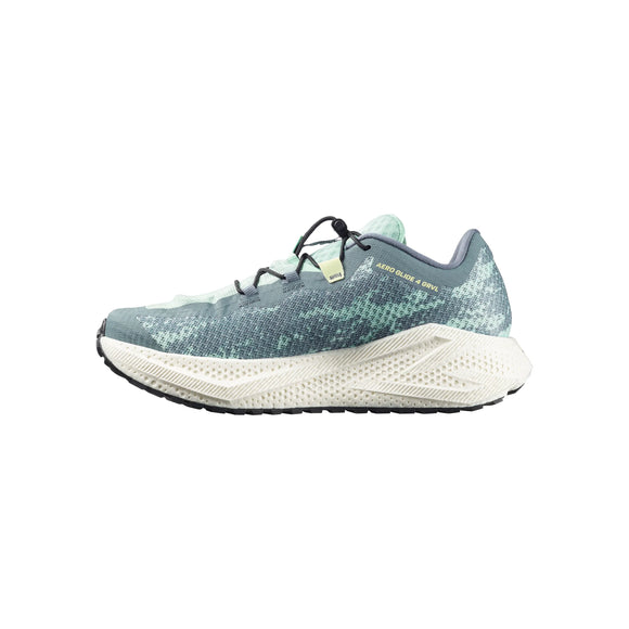 En enkelt Salomon Aero Glide 4 Grvl herre gravel løbesko med maksimal dæmpning ses i profil. Skoen har en stormy weather/lichen/vanilla ice overdel, hvid sål, sort ydersål og sort snørebånd, vist mod en hvid baggrund.