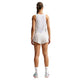En person med langt tilbagestrøget hår står med ryggen til og er iført en Nike AeroSwift Cropped Tank Top, Dame, Off White/Black, sammen med hvide shorts, sokker og sportssko med farverige såler på en almindelig hvid baggrund.