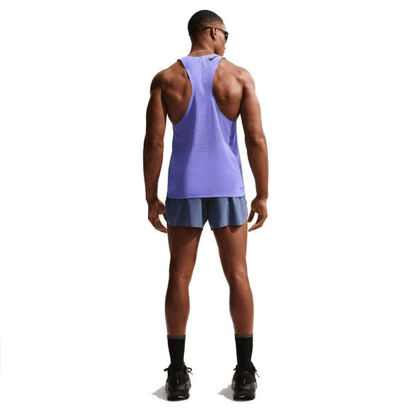 En mand står med ryggen til iført Nike AeroSwift Running Singlet, Herre, Sapphire/Black, blå løbeshorts, sorte sokker og sportssko samt solbriller - klar til løbetræning på en almindelig hvid baggrund.
