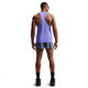 En mand står med ryggen til iført Nike AeroSwift Running Singlet, Herre, Sapphire/Black, blå løbeshorts, sorte sokker og sportssko samt solbriller - klar til løbetræning på en almindelig hvid baggrund.