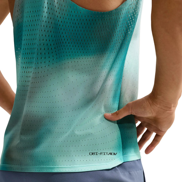 En person iført en Nike AeroSwift løbetrøje til mænd i farven Bright Spruce/Green står med den ene hånd på hoften. Dette eksklusive løbetøj til mænd har små huller og teksten »Dri-FIT ADV« nær nederkanten, hvilket sikrer optimal åndbarhed og komfort. Kun overkroppen og en del af shortsene er synlige.