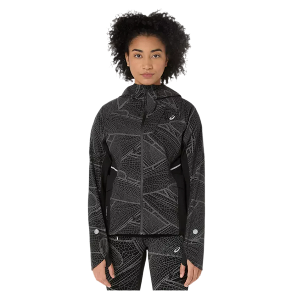 En person med krøllet hår viser Asics Limited Series Lite-Show Jacket, Dame, i Performance Black og geometrisk mønstrede bukser frem mod en hvid baggrund. Jakkens høje krave skiller sig ud.