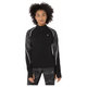 En kvinde med krøllet hår bærer den sorte Asics Limited Series Lite-Show Ls Top til kvinder med reflekterende detaljer og mønstrede ærmer sammen med matchende leggings, der står på en almindelig hvid baggrund.