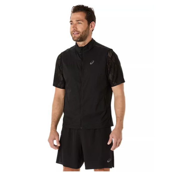 En mand med kort mørkt hår og skæg er iført Asics Metarun Packable Gilet, Herre, Performance Black over en sort skjorte og shorts - alle med Asics-logo. Han kigger lidt til venstre og smiler.