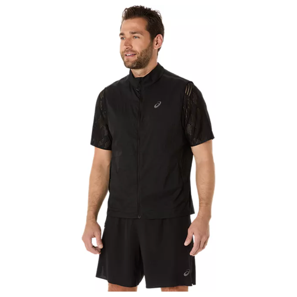 En mand med kort mørkt hår og skæg er iført Asics Metarun Packable Gilet, Herre, Performance Black over en sort skjorte og shorts - alle med Asics-logo. Han kigger lidt til venstre og smiler.