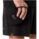 En person i sorte sportsshorts holder en lille, rund, sort SOUND BODY-pose i den elastiske strop - ideel til løbere, der ønsker en ultralet vest som Asics Metarun Packable Gilet, Herre, Performance Black.