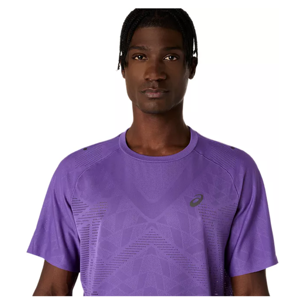 En person med kort, flettet hår kigger fremad mod en almindelig hvid baggrund iført Asics Metarun Ss Top til mænd i Edo Purple, der er fremstillet af fugttransporterende materiale.