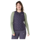 En person ser frem for sig i en Asics Nagino Run Padded Gilet, Dame, Indigo Fog, med lynlås over en lysegrøn langærmet top og mørke leggings. Et lille logo på brystet er synligt. Baggrunden er almindelig hvid.