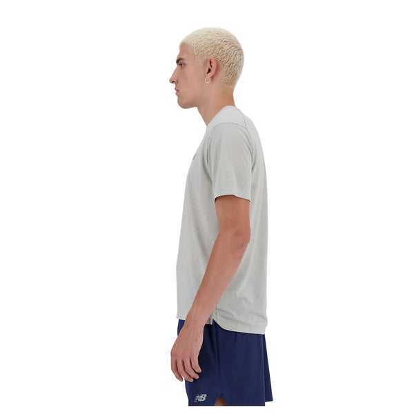 En person med kort, afbleget blondt hår ses i profil iført en grå New Balance Athletics T-shirt (Herre) på en hvid baggrund.