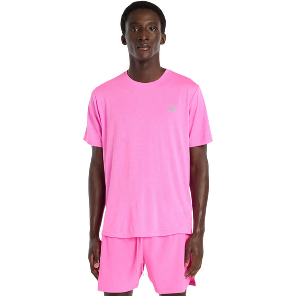En person står og kigger fremad iført en pink New Balance Athletics T-Shirt, Herre, Pink Heat Heather. T-shirten har et lille logo på venstre bryst. Baggrunden er helt hvid.