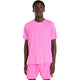 En person står og kigger fremad iført en pink New Balance Athletics T-Shirt, Herre, Pink Heat Heather. T-shirten har et lille logo på venstre bryst. Baggrunden er helt hvid.