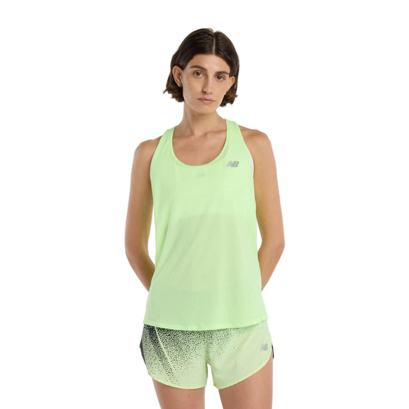 En kvinde med kort brunt hår er iført en lysegrøn New Balance Athletics Tank, Dame, i Afterglow Heather/Slate Grey med matchende prikkede shorts i åndbart materiale og står på en almindelig hvid baggrund.