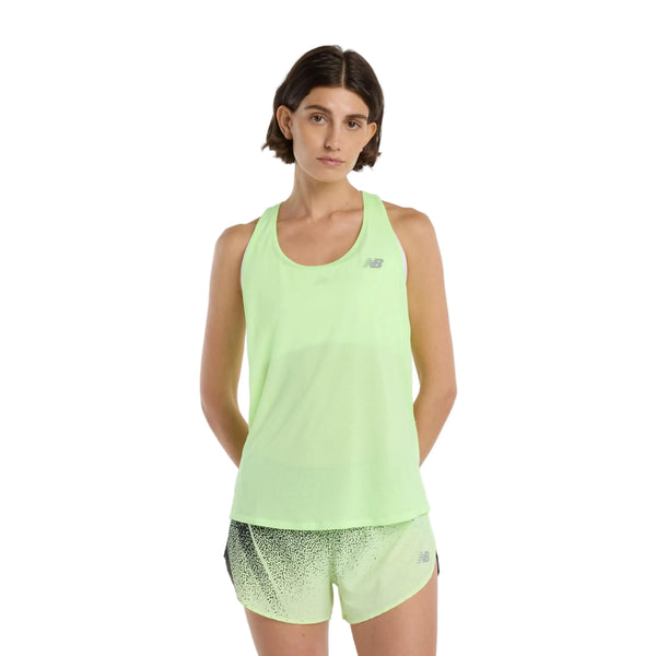 En kvinde med kort brunt hår er iført en lysegrøn New Balance Athletics Tank, Dame, i Afterglow Heather/Slate Grey med matchende prikkede shorts i åndbart materiale og står på en almindelig hvid baggrund.