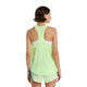 En kvinde med kort brunt hår ses bagfra iført en New Balance Athletics Tank, Dame, Afterglow Heather/Slate Grey, en hvid sports-bh og grønmønstrede sportsshorts. Baggrunden er helt hvid.