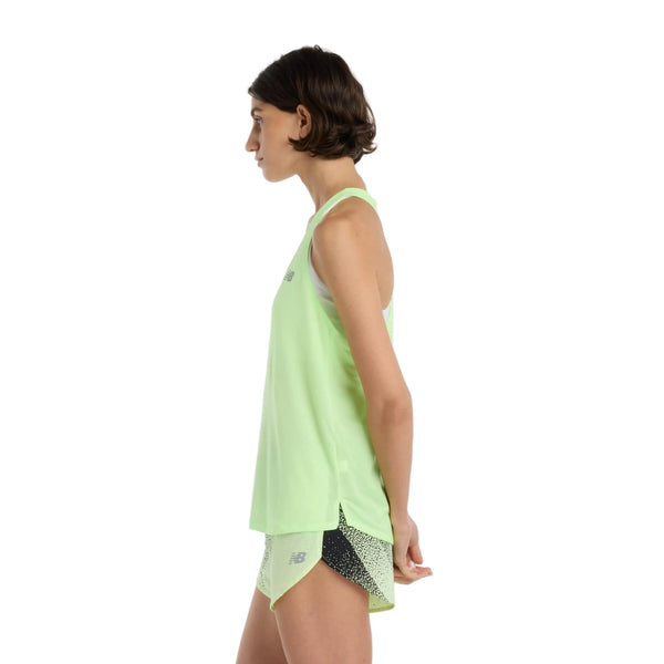 En person står i profil iført en New Balance Athletics Tank, Dame, Afterglow Heather/Slate Grey med matchende prikkede shorts og hænderne foldet bag ryggen mod en almindelig hvid baggrund. Toppen er fremstillet af åndbart materiale.
