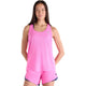 En kvinde kigger fremad i en lyserød New Balance Athletics Tank, Dame, Pink Heat Heather/Slate Grey, sammen med matchende shorts. Hun har langt brunt hår og et neutralt udtryk, som fremhæver denne stilfulde tanktop til kvinder.