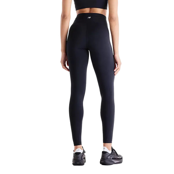 En person iført en sort sports-BH, sorte New Balance Athletics Heat High Rise Legging 27″ med NB HEAT-teknologi og sorte sneakers står med ryggen til kameraet foran en hvid baggrund. Disse avancerede Athletics Heat High Rise Legging 27″ til kvinder fra New Balance er designet med henblik på både komfort og ydeevne.