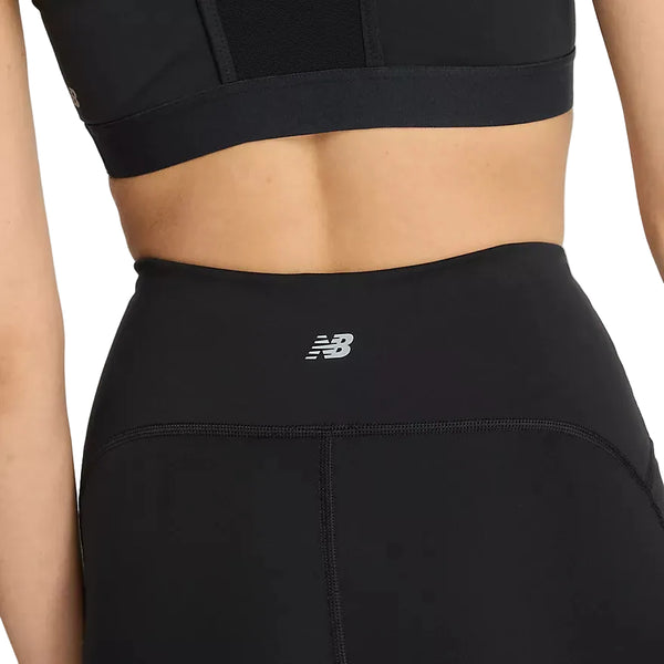 Nærbillede af en person, der bærer New Balance Athletics Heat High Rise Legging 27″ i sort, kombineret med en matchende sports-BH. New Balance-logoet ses på leggingsens linning, som er udstyret med den innovative NB HEAT-teknologi. Billedet fokuserer på personens side og nedre del af ryggen.