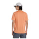 En person iført en lys orange New Balance Athletics T-shirt, Herre, Aae med hurtigtørrende teknologi, grå shorts og en hvid baseballkasket står med ryggen til kameraet mod en hvid baggrund.