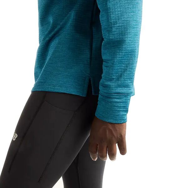 En person iført en blågrøn New Balance Athletics Heat Grid 1/2 Zip og sorte sportsleggings.
