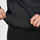 En person bruger begge hænder til at løfte kanten på Saysky Blaze Half zip Light-weight Fleece, Herre, Sort, og afslører dermed den indvendige struktur i det letvægtige fleecestof. Iført matchende sorte bukser viser vedkommende, hvordan denne svedafvisende løbetrøje forener komfort og funktionalitet. Baggrunden er enkel og lys.