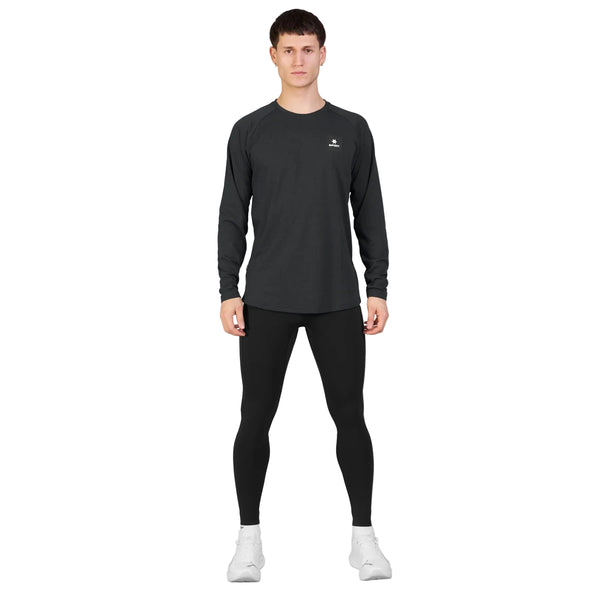 En person står med ansigtet vendt fremad foran en ensfarvet hvid baggrund og har den sorte Saysky Blaze langærmede, lette fleece til mænd på, kombineret med sorte leggings og hvide sportssko.