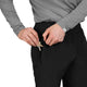 Der ses en person iført en grå langærmet trøje og sorte bukser – nærmere bestemt Saysky Blaze Pants, Unisex, Black – der putter en nøgle i lommen med lynlås på disse træningsbukser. Personens ansigt kan ikke ses.