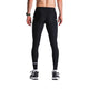 En mand iført Fusion Long Tight Unisex SuperBlack-leggings, sorte og hvide HOKA-løbesko og et grønt ur står i bar overkrop og kigger væk fra kameraet på en almindelig lysegrå baggrund.
