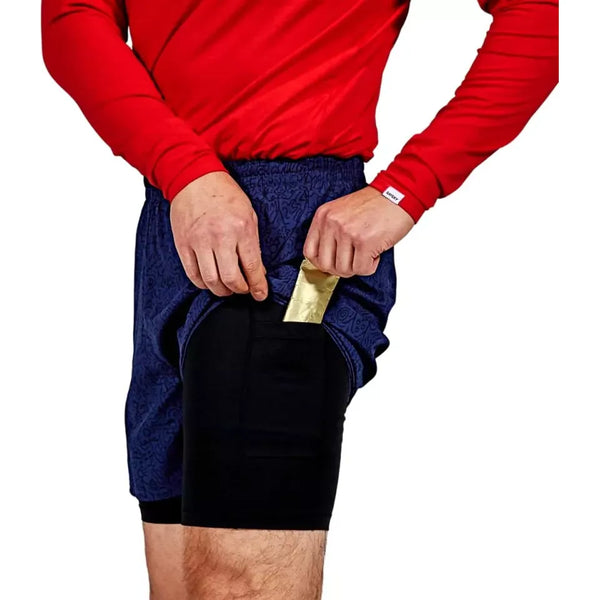 En person i rød langærmet skjorte lægger en guldindpakket genstand i sidelommen på Saysky CC Pace 2 in 1 Shorts 5", Herre, Blue - ideelle løbeshorts til maratonløbere. Billedet viser torso og overben med sort underlag.