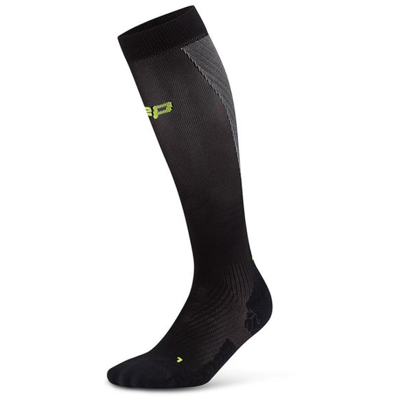 En enkelt CEP Core Run Ultralight Compression Sock til mænd i sort/grå med gult logo i toppen, diskret gråt mønster og forstærket hæl, tå og ankel vises på en hvid baggrund.