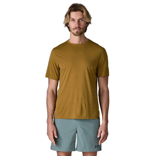 En mand med lysebrunt hår og skæg er iført en Patagonia Capilene Cool Ultra Shirt, Herre, Bobcat Brown - Light Bobcat Brown X-Dye og lyseblå shorts på en almindelig hvid baggrund.