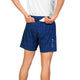 En person iført en hvid skjorte og Saysky Checker Pace Shorts 5″ (Herre, Blue Checker) tager en gul genstand frem fra baglommen. På venstre side af træningsshortsene ses hvide symboler og japanske tegn. Personen ses bagfra, fra taljen til midt på låret.