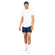 En mand står foran en hvid baggrund iført en hvid T-shirt, Saysky Checker Pace Shorts 5″ i Blue Checker, hvide strømper, hvide sneakers og en blå kasket. Dette klassiske herrelook forener afslappet stil og atletisk funktionalitet med højtydende shorts designet af Saysky, der sikrer komfort hele dagen. Han står med ansigtet vendt fremad, venstre arm afslappet ned langs siden og højre arm let bøjet.