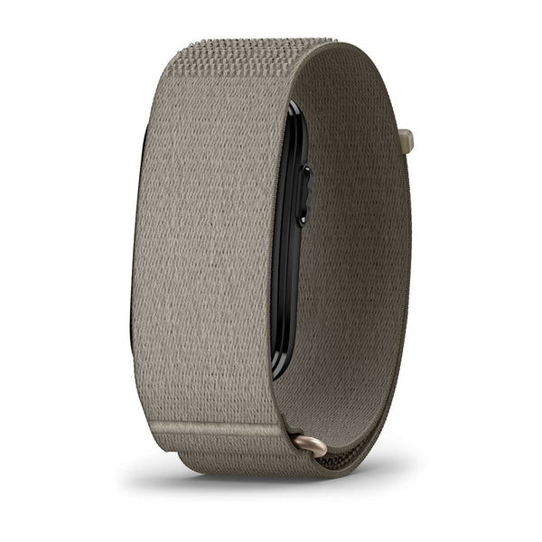 Et Garmin Cirqa Smart Band i farven »French Grey« vises set bagfra, hvor dets rektangulære urskive er delvist synlig, og det er udstyret med en struktureret, lysegrå stofrem, alt sammen mod en ensfarvet hvid baggrund.