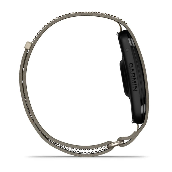 Set fra siden: Garmin Cirqa Smart Band i farven »French Grey« med en elegant sort skærm og et slankt, struktureret armbånd med en kant med løkkeformet design og lås. Denne enhed, der også kaldes et »aktivitetsarmbånd«, forener stil og funktionalitet med funktioner som søvnregistrering. Garmin-logoet ses på siden af smarturet.