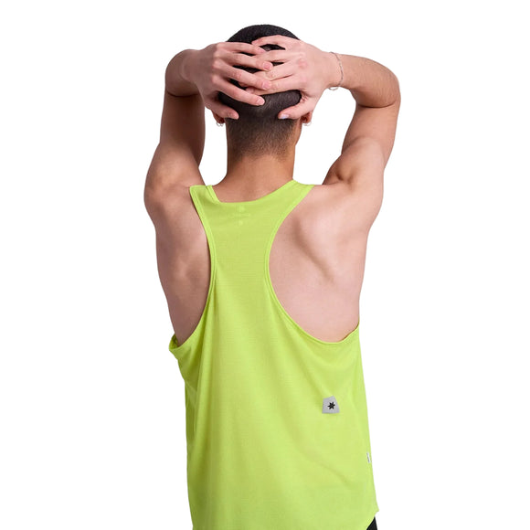 En person i en ærmeløs, lysegrøn Saysky Reactive Flow Singlet (Herre, gult logo) står med ryggen til kameraet, armene løftet og hænderne foldet bag hovedet mod en almindelig hvid baggrund.