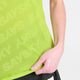 En person iført en lysegrøn Saysky Reactive Flow T-shirt, Herre, gult logo holder om kanten med højre hånd. Armen er let bøjet, sorte shorts er delvist synlige, og baggrunden er almindelig hvid.