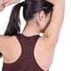 Der ses en person set bagfra med langt, mørkt hår sat op i en hestehale. Personen har en Saysky W Clean Combat Pro Singlet til kvinder i farven Burgundy på og strækker den ene arm over hovedet. Baggrunden er helt hvid.
