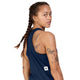 En person med mellembrun hudfarve og flettet hår har Saysky Clean Combat Pro Singlet, Dame, Blå på og kigger over skulderen. Tatoveringer af en skorpion, en kat, en ørn og geometriske mønstre kan ses på overarmen, skulderen og ryggen. Det hurtigtørrende sportstøj fra Saysky sikrer komfort under træning. Hvid baggrund.