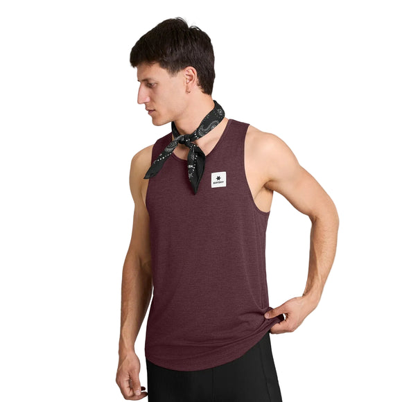 En person iført en Saysky Clean Combat Pro Singlet, Herre, i farven Burgundy, med et hvidt logo-mærke og en sort bandana bundet om halsen, ser ned og retter singletten med den ene hånd. DELTAPEAK Carat-stoffet giver dette herreoutfit et eksklusivt udtryk, alt sammen på en ensfarvet hvid baggrund.