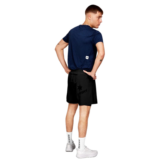 En mand står med ryggen til og er iført Saysky Clean Combat Pro T-Shirt, Herre, Blue, sorte shorts, hvide sokker og sportssko. Denne åndbar t-shirt herre er udstillet mod en almindelig hvid baggrund.
