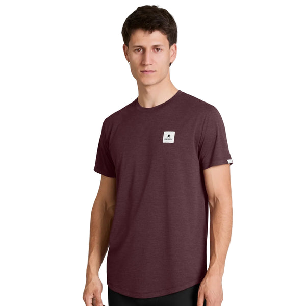 En mand står foran en ensfarvet hvid baggrund og ser ind i kameraet med et neutralt udtryk, iført Saysky Clean Combat Pro T-shirt, Herre i farven Burgundy – en kortærmet funktions-T-shirt med et lille hvidt, rektangulært logo på brystet. Denne hurtigtørrende T-shirt sikrer komfort og ydeevne til enhver lejlighed.
