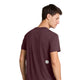 En mand med kort brunt hår står og kigger over skulderen. Han har en Saysky Clean Combat Pro T-shirt på, Herre, i farven Burgundy. Den rødbrune kortærmede T-shirt har et lille hvidt mærke med et sort stjernesymbol nederst på ryggen. Baggrunden er hvid.