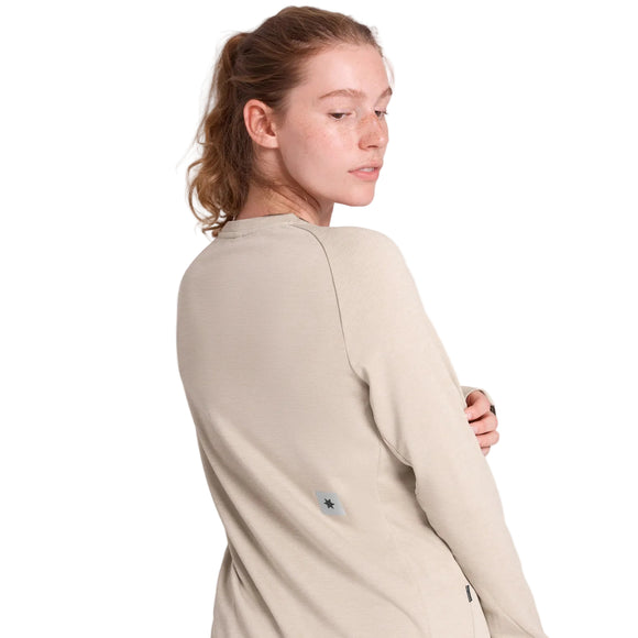 En person har en beige Saysky Clean Flow-trøje med lange ærmer på, hvor der er et lille stjerne-logo på ryggen.