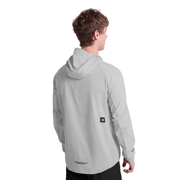En person står med ryggen til kameraet iført en Saysky Clean Pace Flex Hooded Jacket, Herre, Grey - en lysegrå løbejakke til mænd med et lille sort og hvidt mærke nederst på ryggen - og sorte bukser.