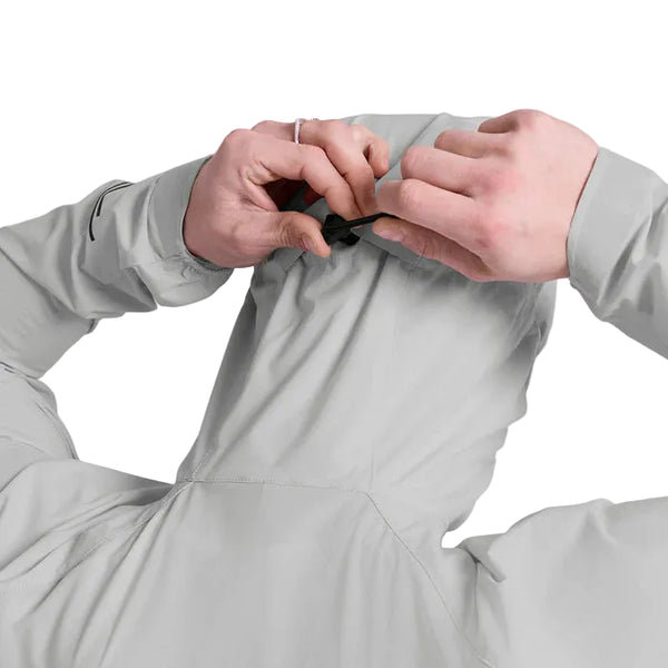 En person ses bagfra i færd med at justere hætten på en lysegrå Saysky Clean Pace Flex Hooded Jacket, Herre. Denne vindtætte jakke er ideel som løbejakke herre til udendørs løbeture.
