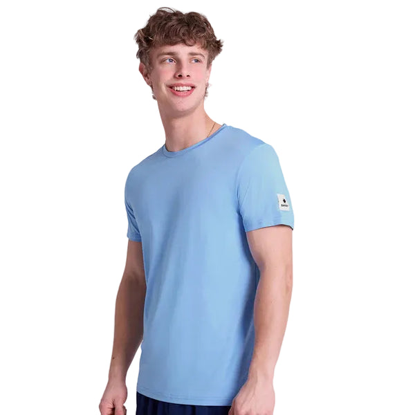 En ung mand med kort krøllet hår er iført en Saysky Clean Pace Running T-shirt, Herre, Blue, og mørke shorts. Han står smilende og kigger lidt til venstre mod en hvid baggrund.